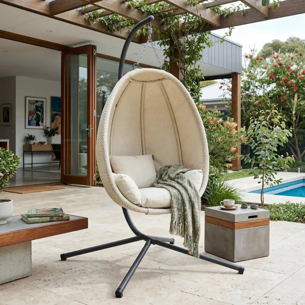 Beige Hanging Egg Chair with Stand and Cushion on Patio